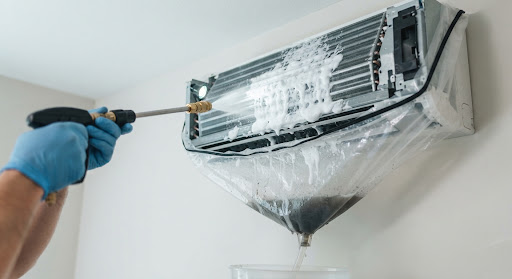 Power pressure washer nozzle spraying antibacterial white foam deeply into indoor AC cooling evaporator fins with drainage bag