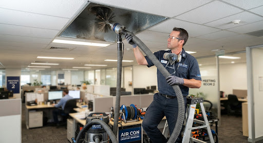 HVAC duct cleaning specialist inserting high powered flexible vacuum hose and rotating brush whip into ceiling duct